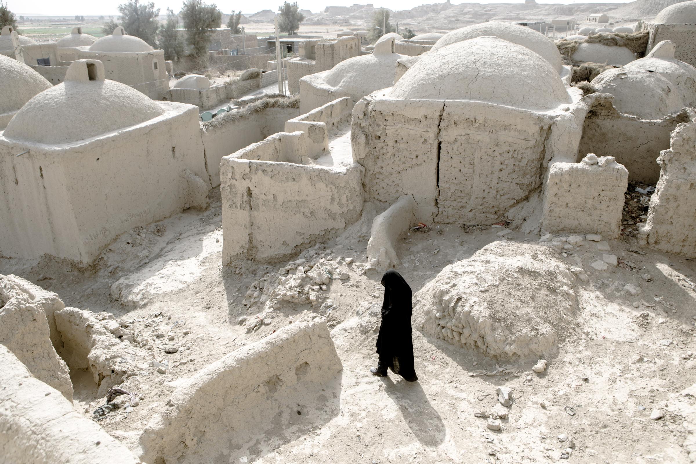 IN THE DESERT OF WETLANDS -   A local woman walks through the mud houses of the...