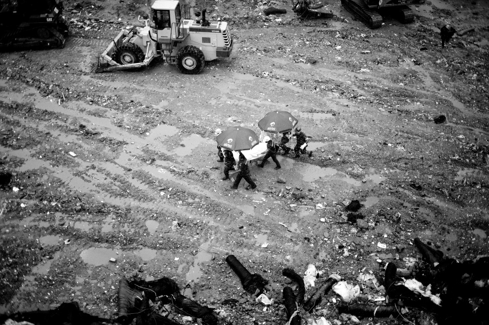Under the rubble - Rescuers carry a worker found dead inside the rubble of...