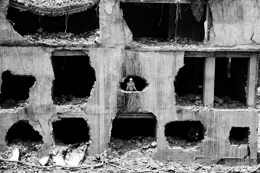 Under the rubble - A rescue worker stands at the wreckage of the Rana Plaza...
