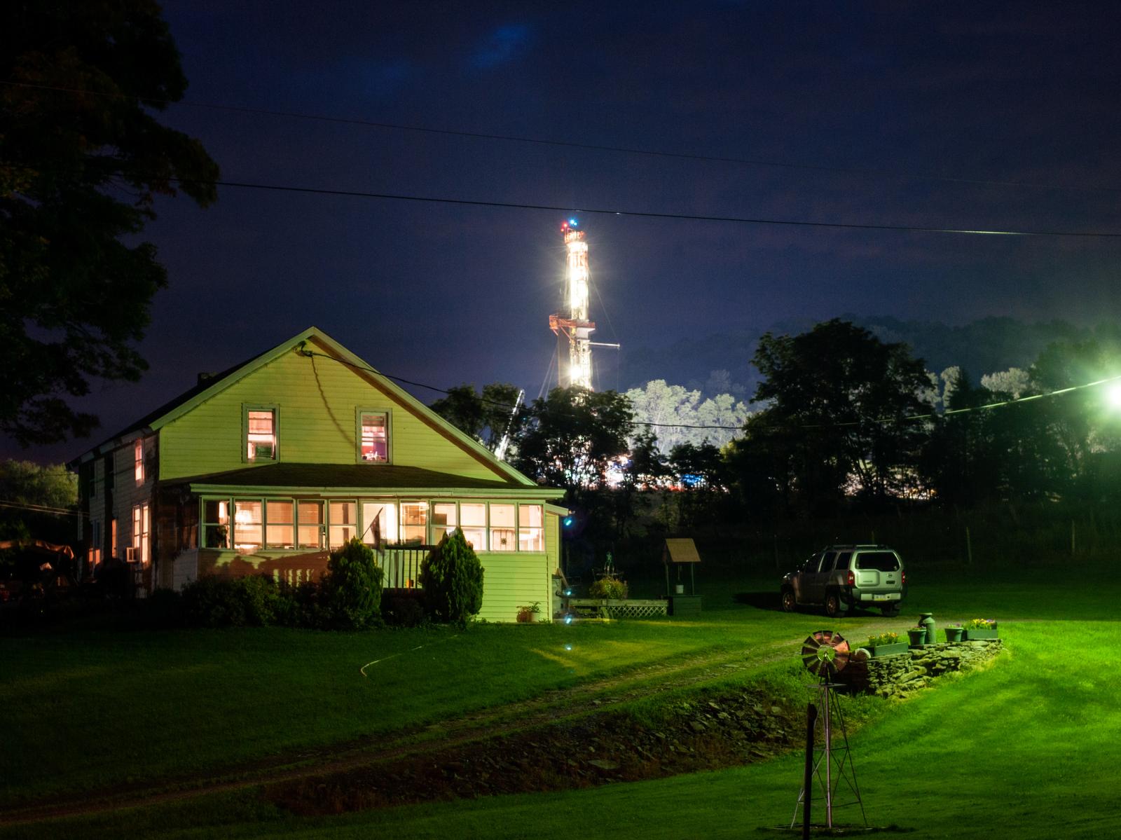 A gas drilling rig is seen behind a home in Springville, PA USA