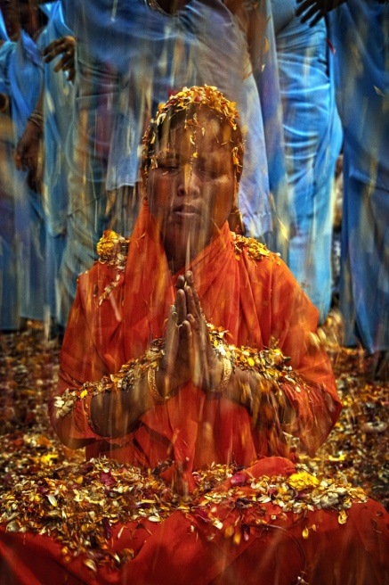 Path breaking move - A widows prays under a rain of petals and flowers during...