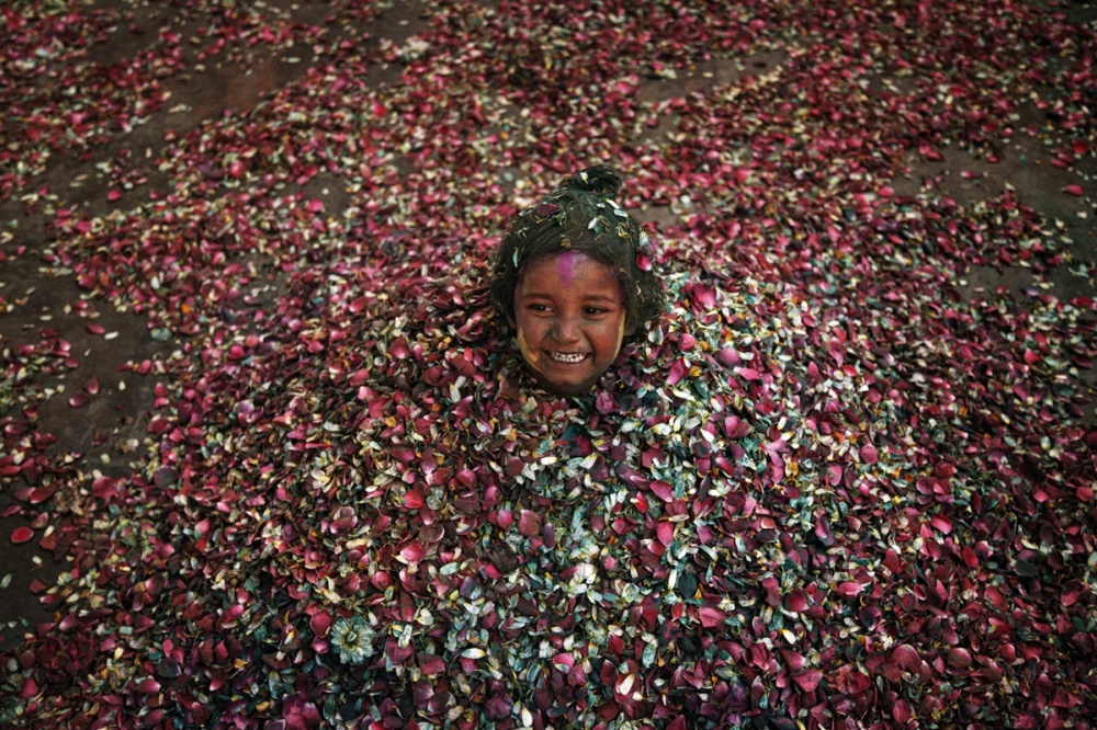 Path breaking move - A girl covered by petals and flowers smiles taking part...