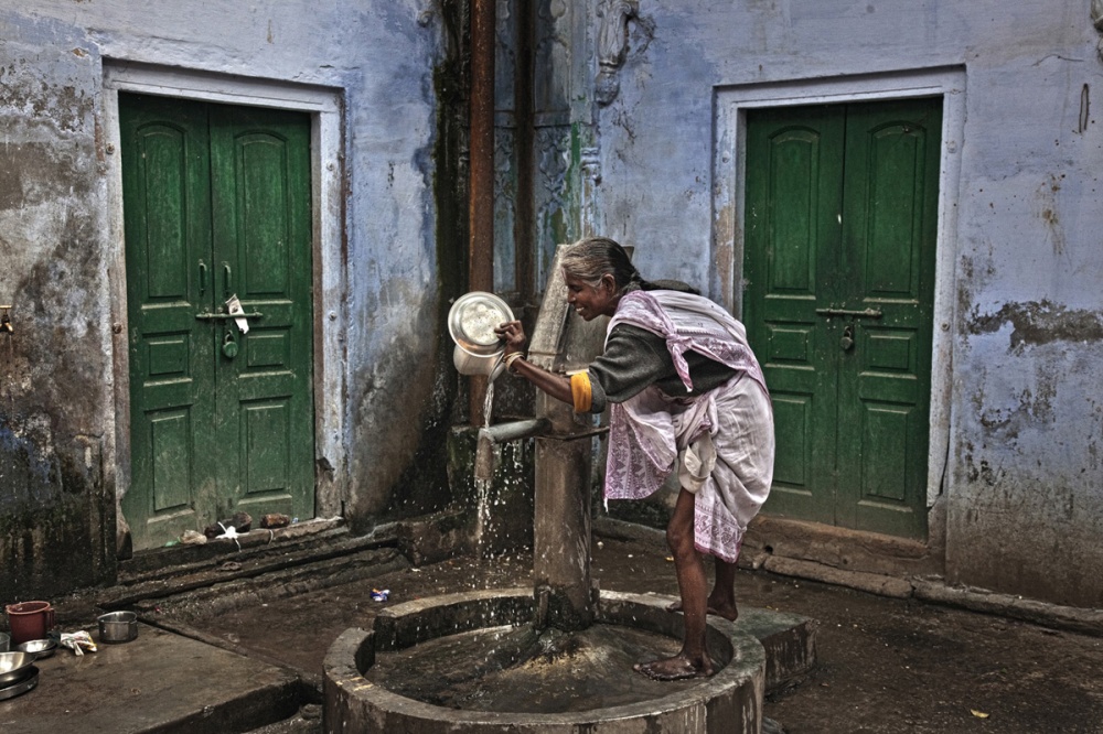 Path breaking move - A widow wash the dishes by the fountain of the old ashram...