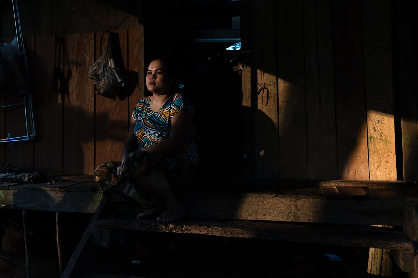 LIFE ON THE OTHER SIDE - Surat Thani - Mithae Mar, a rubber tapper, sits outside...