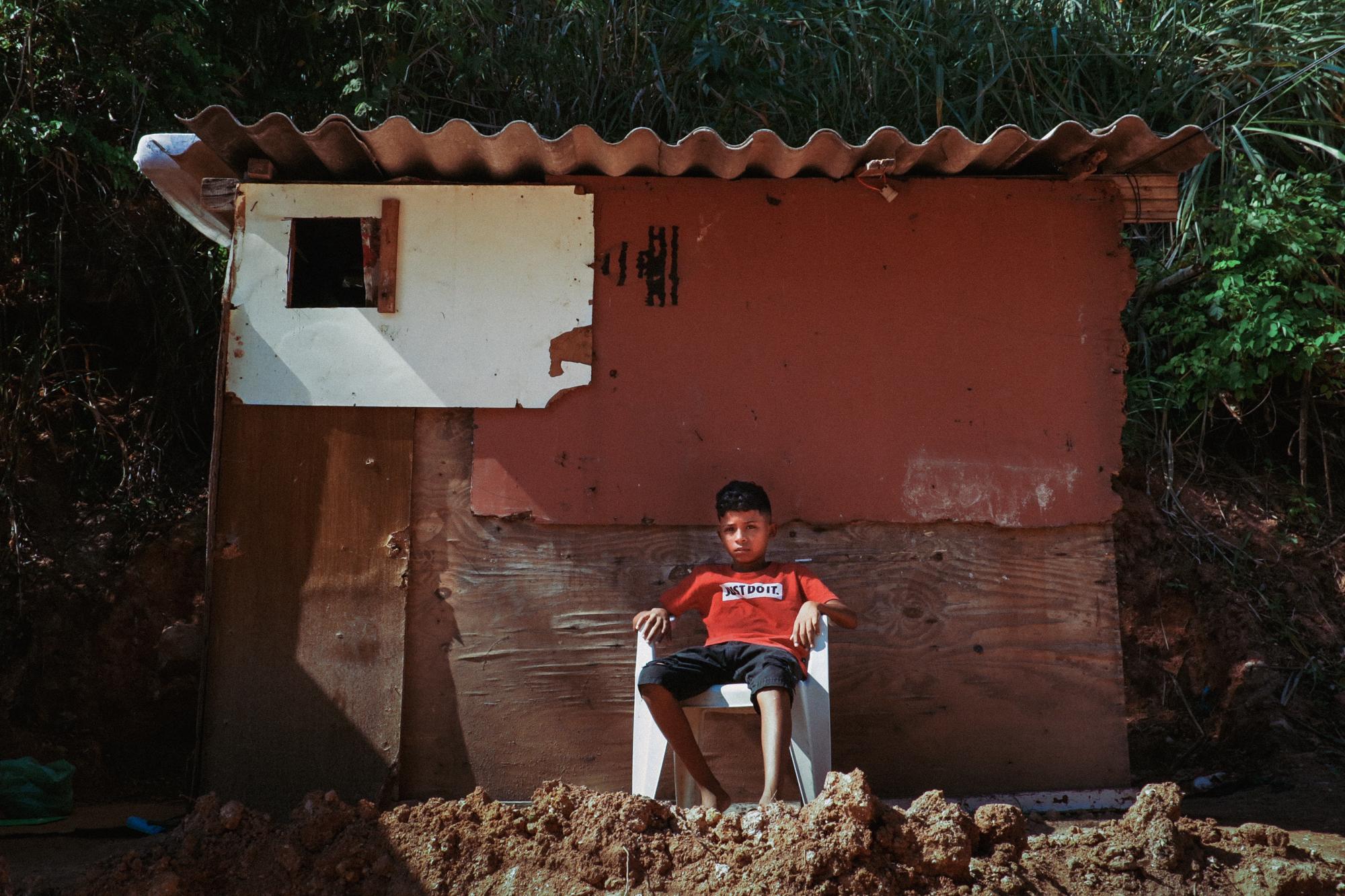 Nós por Nós - Miguel, 7, sits guard outside his single mother's...