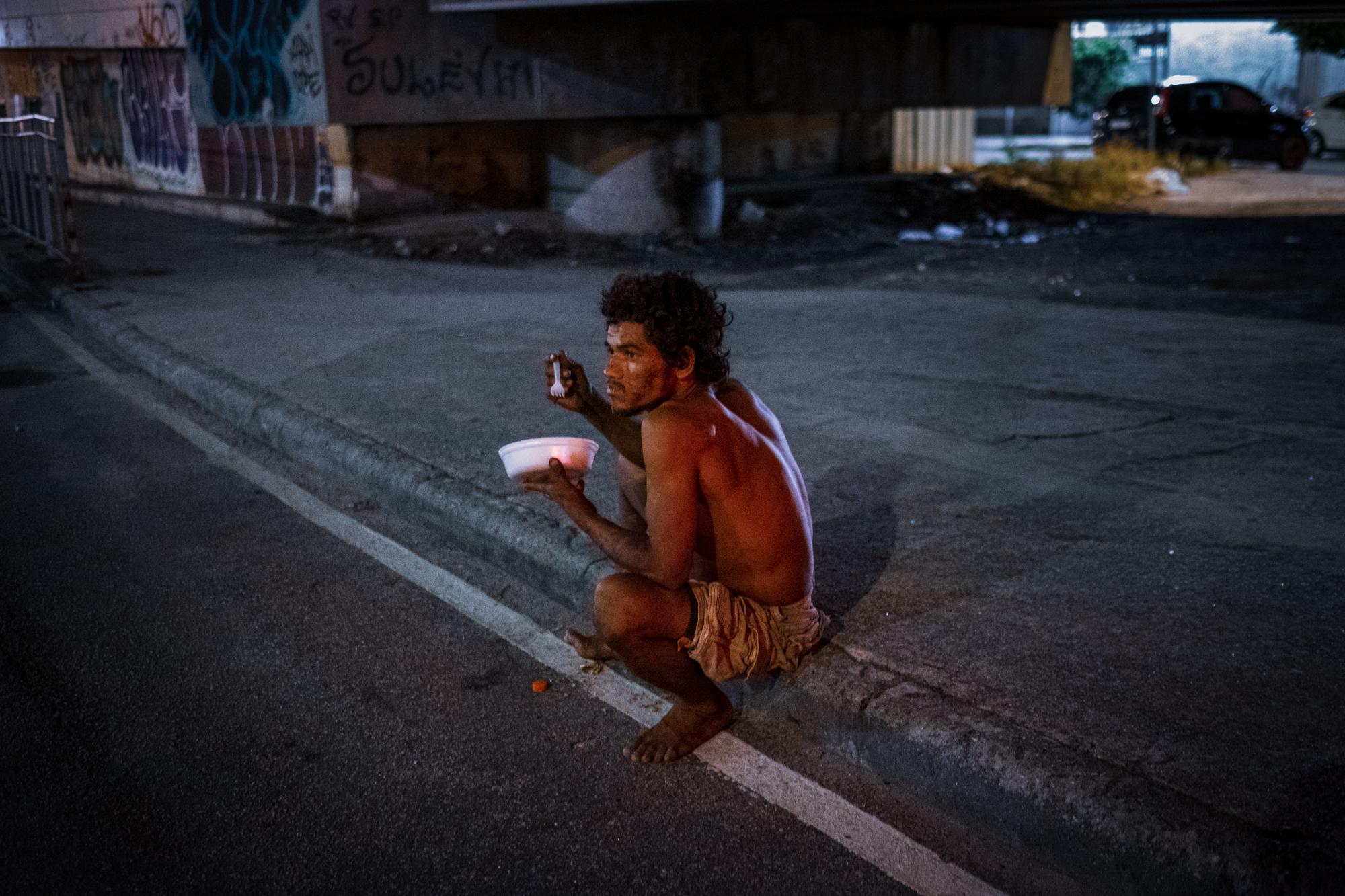 Nós por Nós - A homeless man eating a donated meal in downtown Rio de...