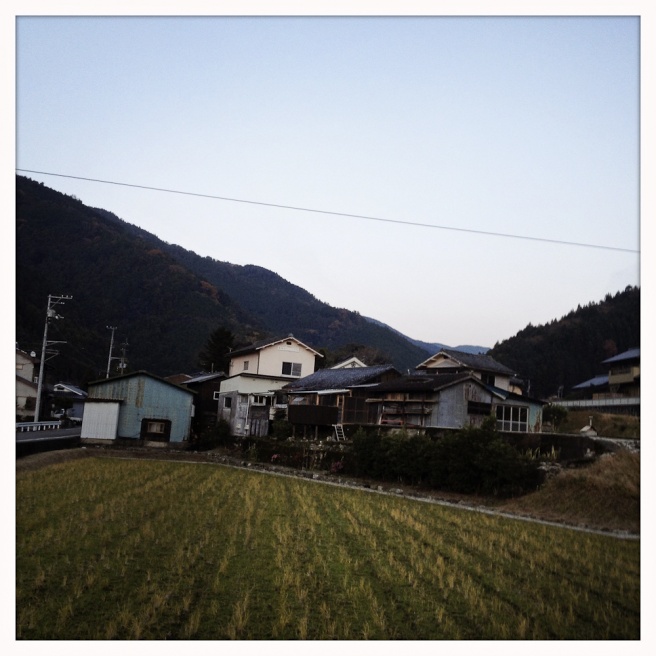 Oda - Lumber garages and old houses sit near a rice field on...