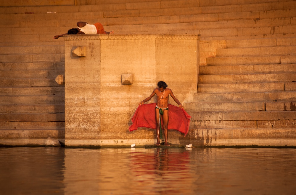 A man baths in the Ganges River and morning sunlight.