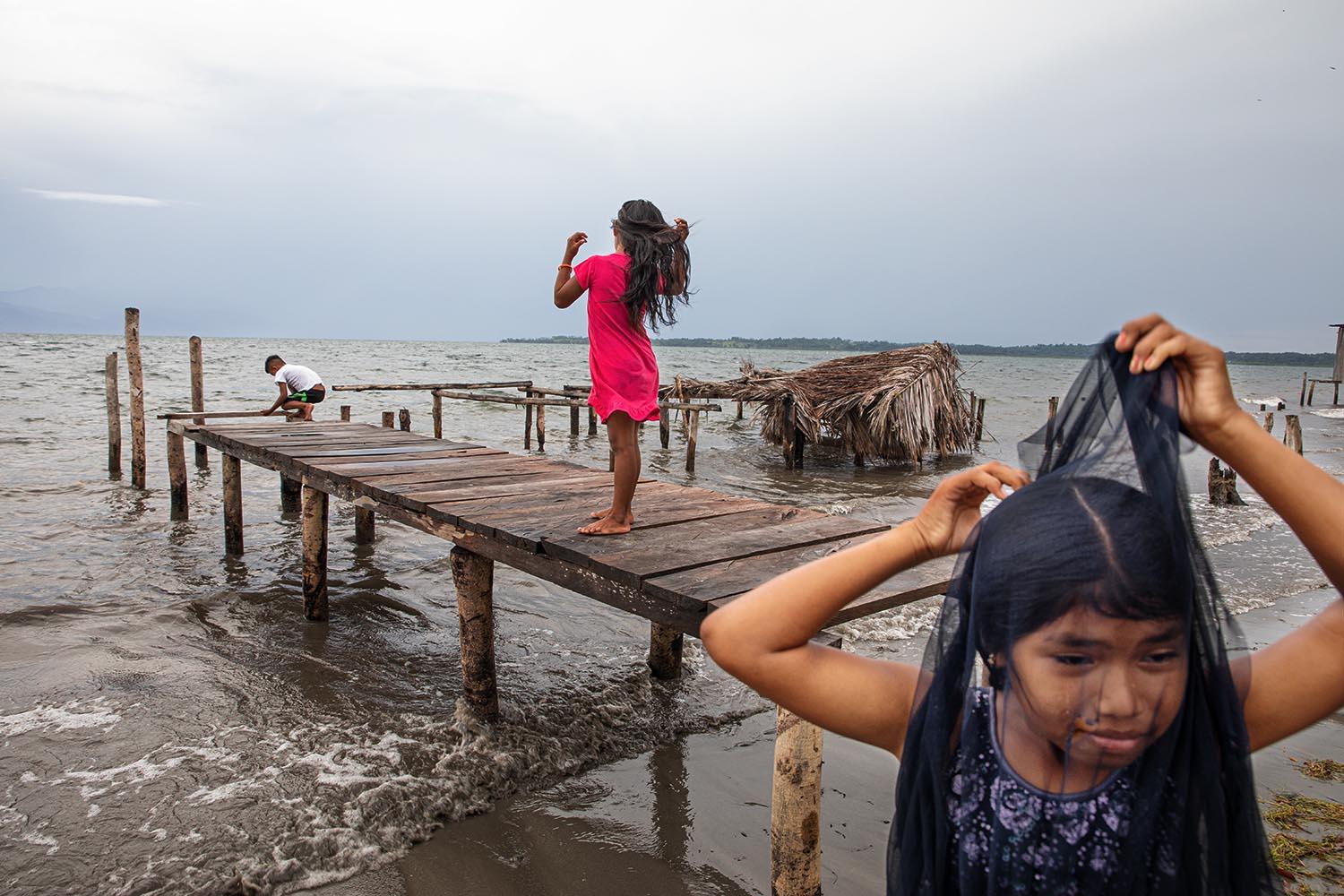 Beyond blue water - Ngäbe girl walks in the beach. Cayo de Agua Island,...