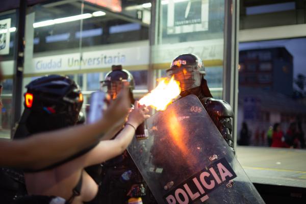Image from Protests - March 8, 2023 - Bogota, Colombia. A protester blazes fire...