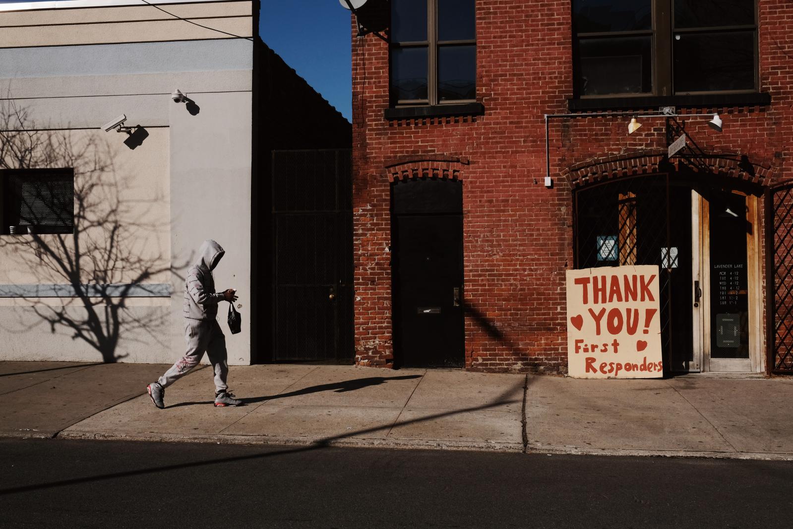 Man passes by a sign thanking first responders in Gowanus.