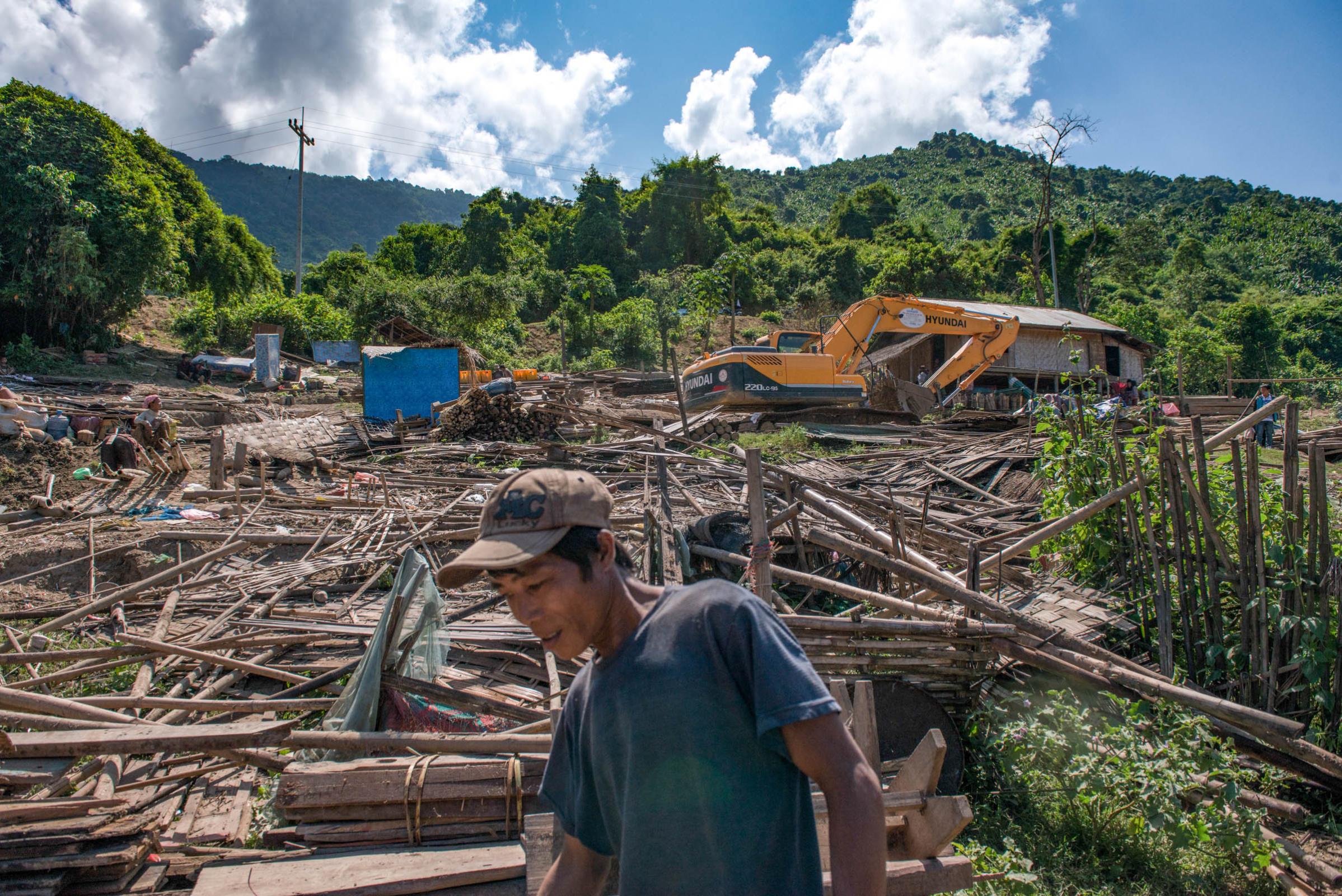 Damming The Mekong River - A villager walks through the building material of houses...
