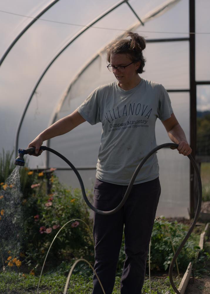 A Spirit of Abundance for Commonweal Magazine - Colleen Fitts waters flowers and herbs in the hoop house.