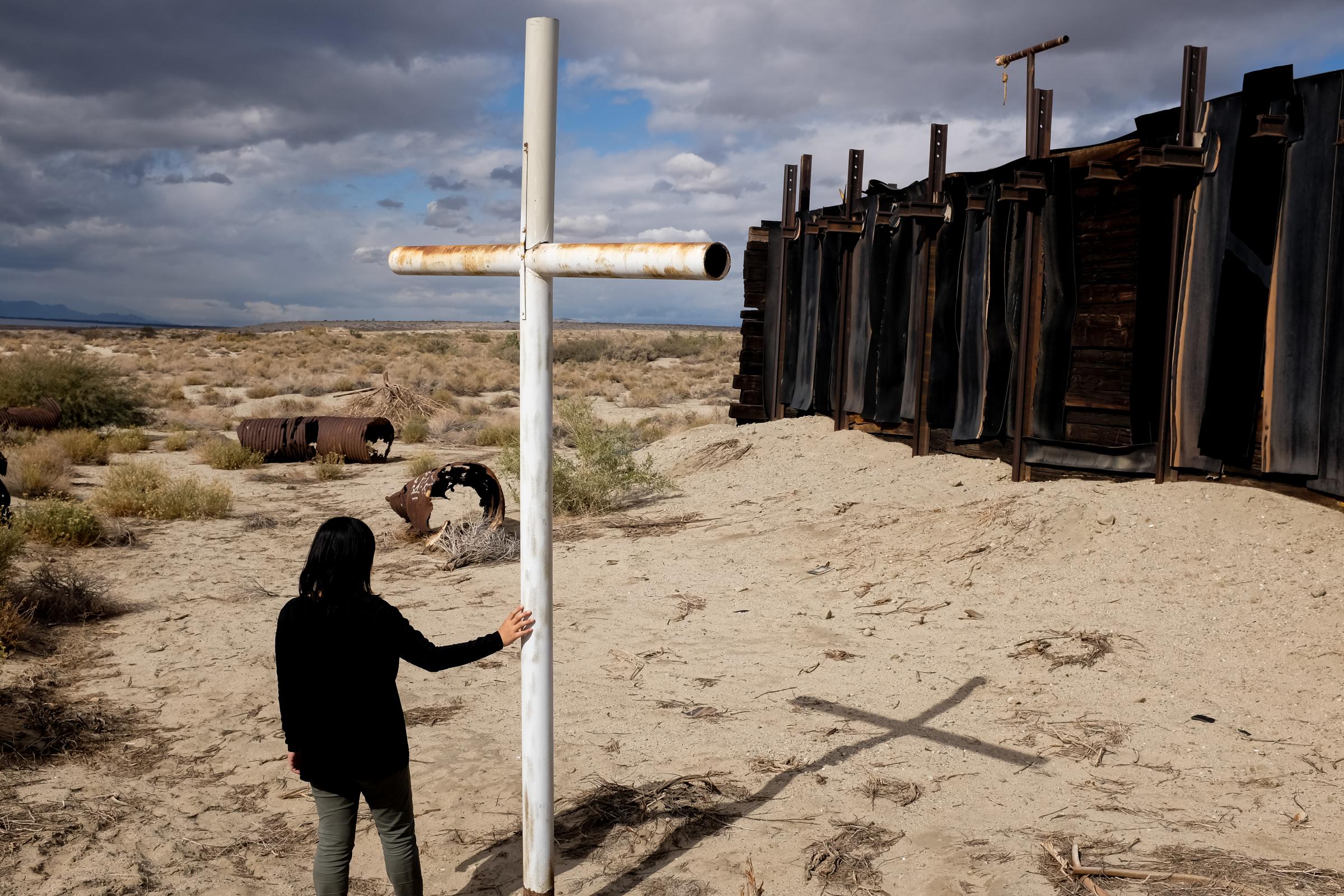 PHOTOGRAPHS - A cross stands next to an old train depot used to shelter...