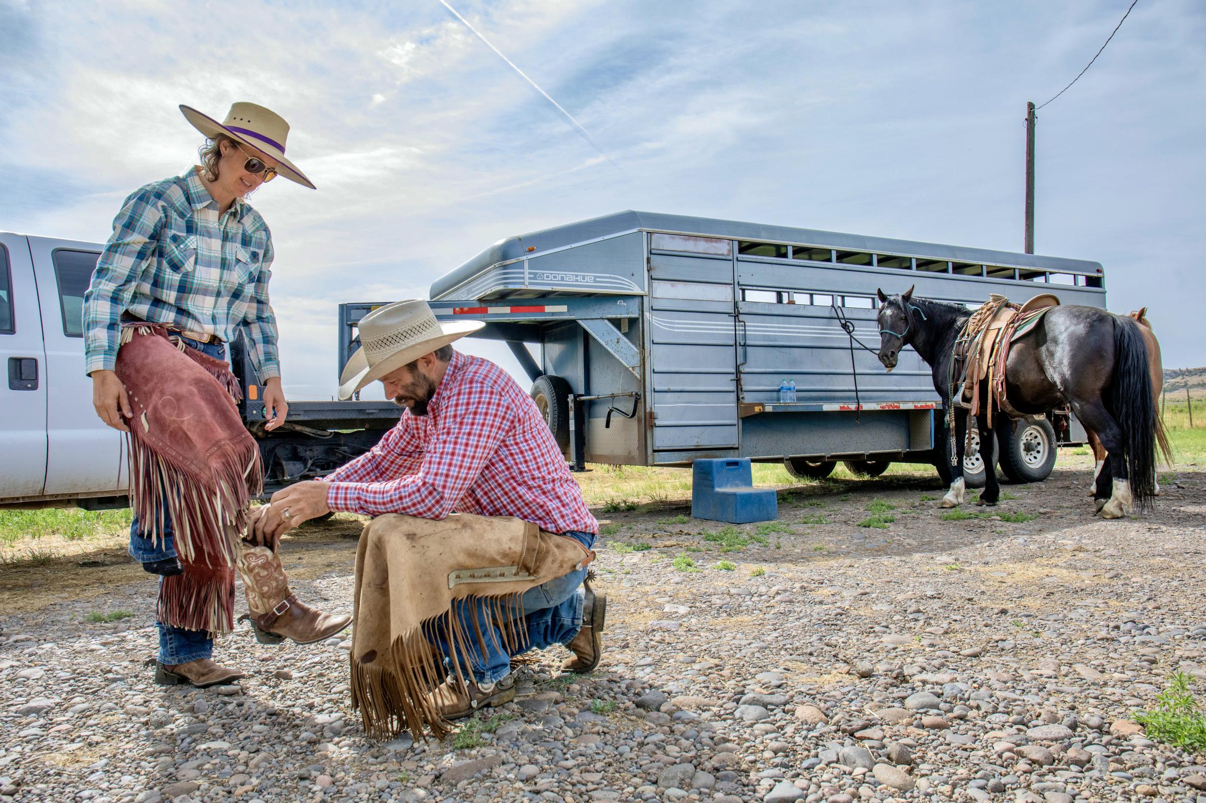 Crisis on the Rio Grande - Kyler Brown helps wife Emily Brown put on boots before the cattle drive the morning of June 21,...