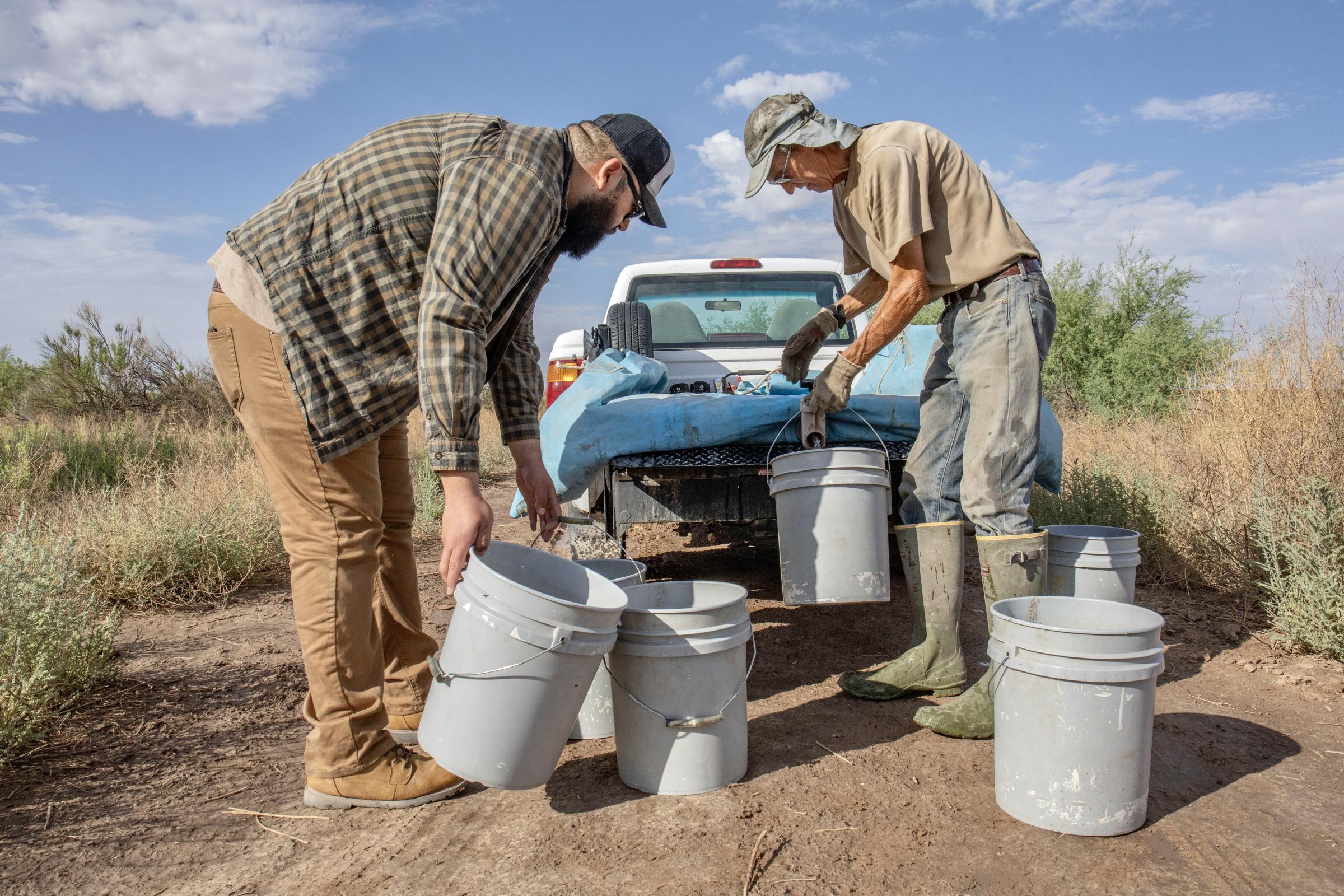 Crisis on the Rio Grande - John Sproul and Sergio Samaniego fill buckets from a water bladder the morning of June 17, 2022....
