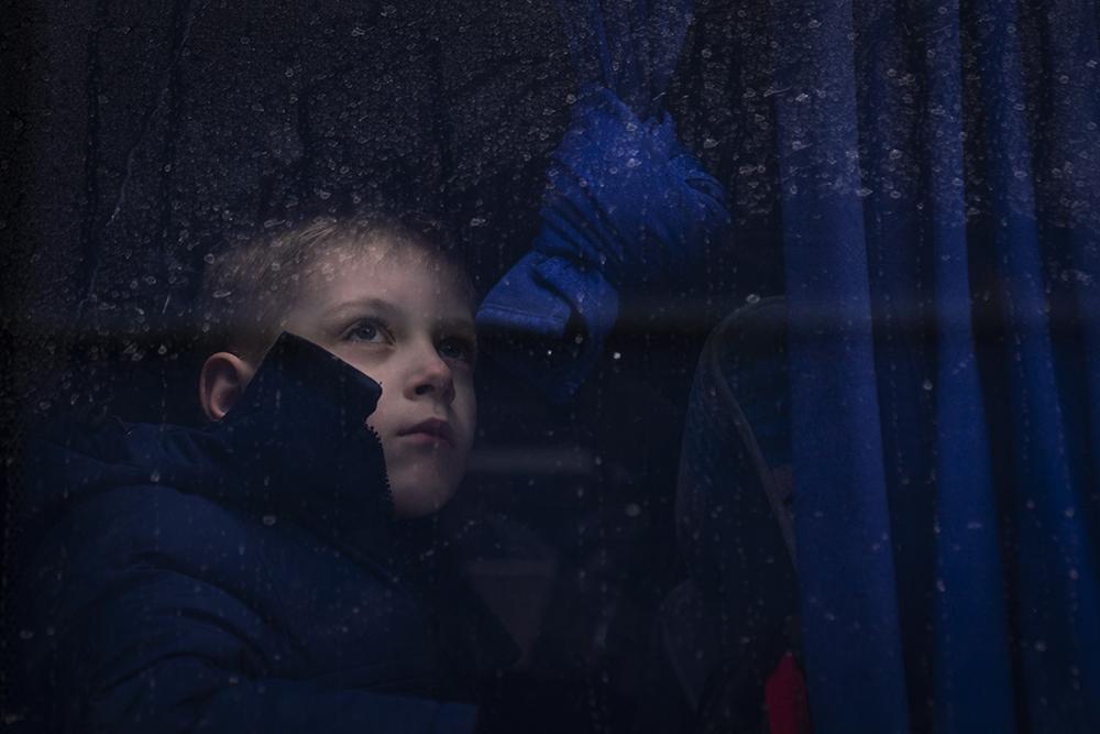 March 2022. An Ukrainian boy looking through a window bus, in the parking area of a shopping mall...