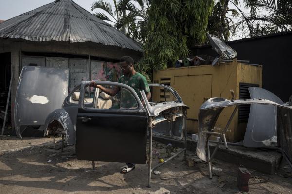Unusual Niger Delta - Diseye Tantua inspects an old Volkswagen beetle that is...