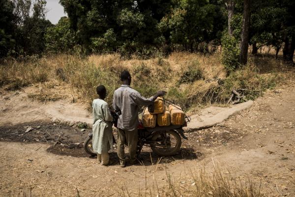 Image from The Water Collectors - Locals transport water on a motorbike after fetching from...