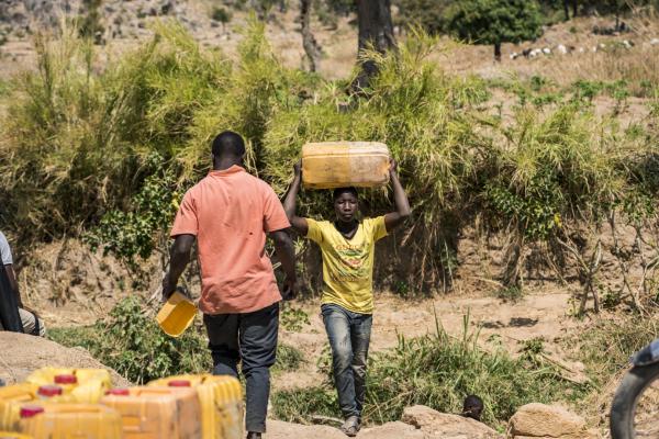 The Water Collectors - A young man carries a jerry can after collecting water...