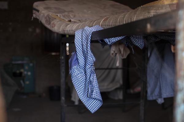 Image from The Negotiator - A student uniform hangs on a double bunk bed in an empty...
