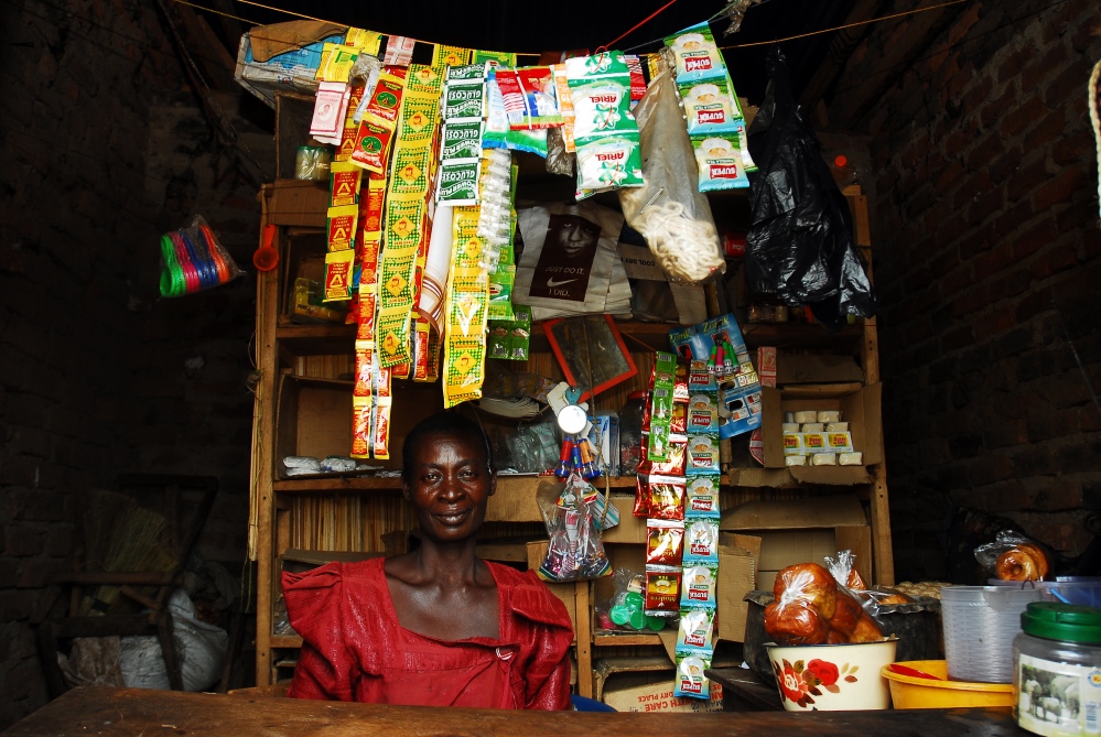  Donatella sits in her store outside Lugala town. The economic autonomy of women has been proven to further economic, social and health successes worldwide yet this is further thwarted due to customary laws which prohibit women from owning land or having assets making them instead more vulnerable to poverty, disease and domestic violence. 