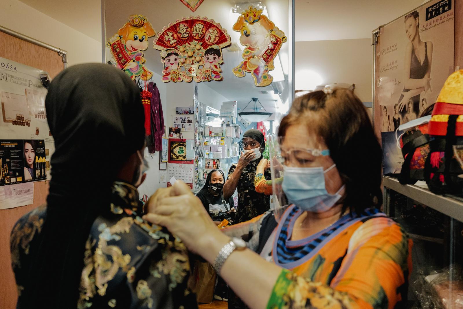 Image from NPR: Two Cantonese Women's Journey: A response to Atlanta Spa Shootings -  Lai twists a button on the cheongsam for a customer. 