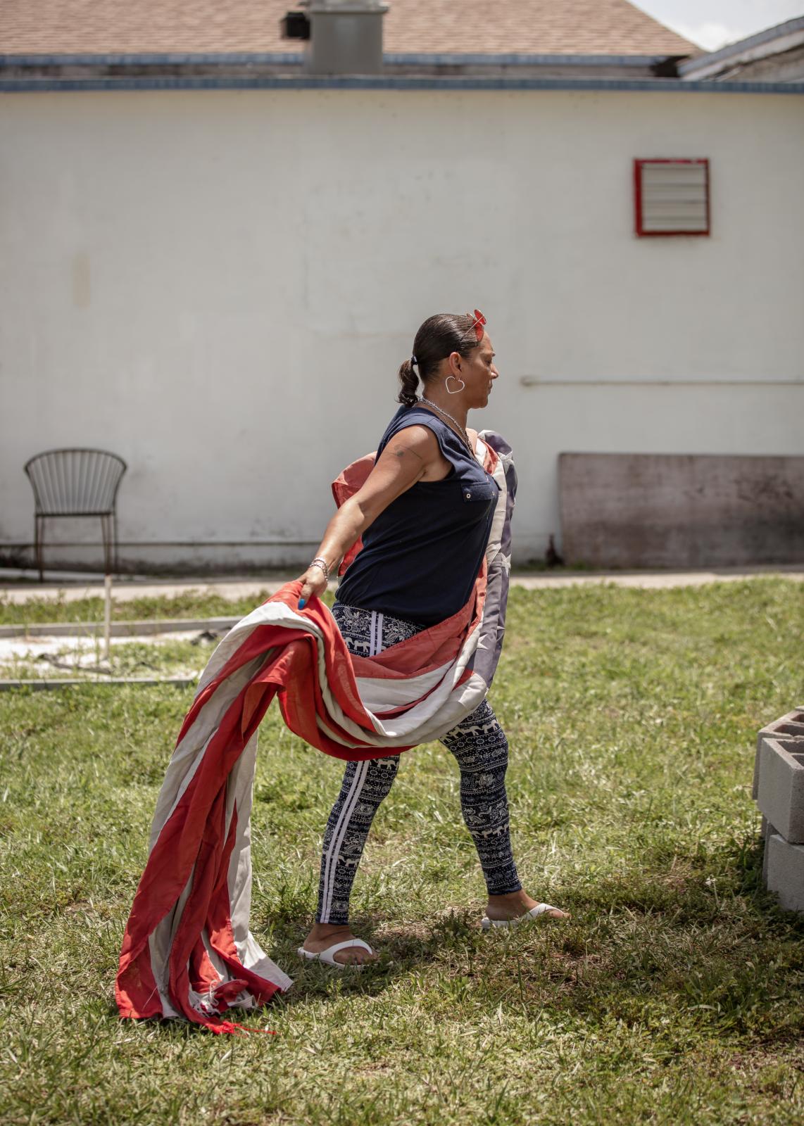 Post 67: American Legion, American Stories - Elaine Salazar, a former post bartender, carries an oversized American flag larger to the fire...