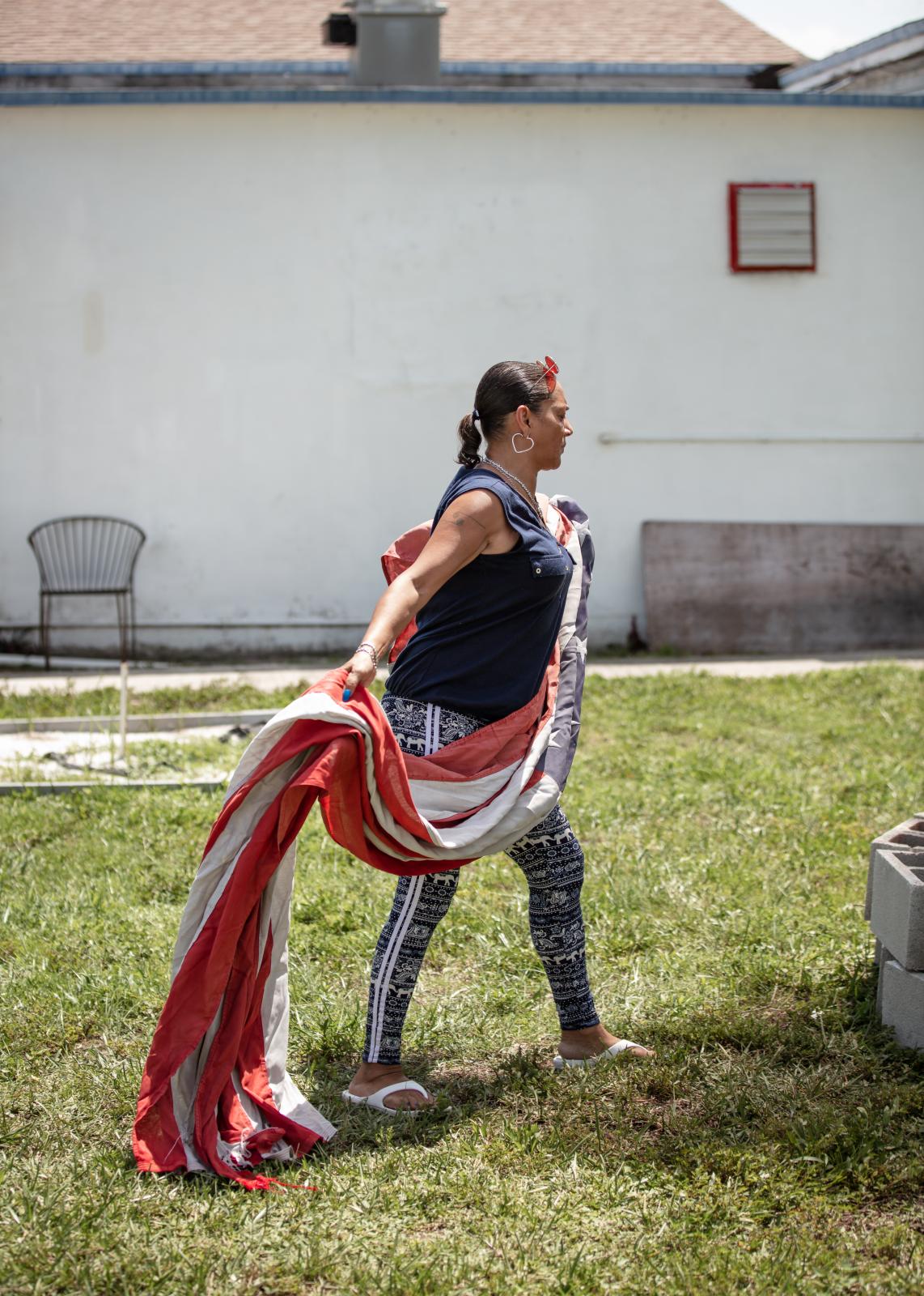 Post 67 - Elaine Salazar, a Post bartender, carries an oversized flag to the fire during the flag...