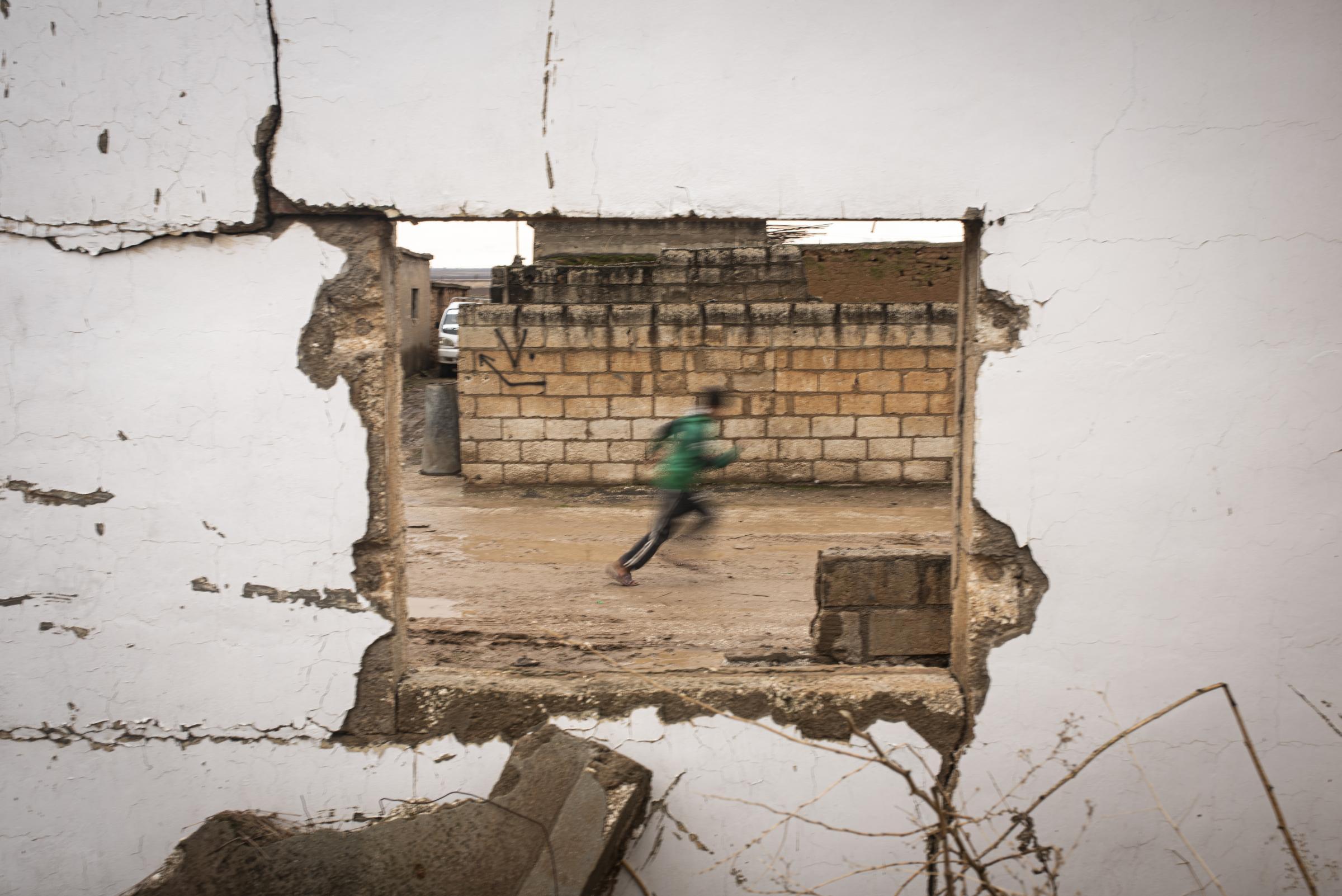 Mud Swings In Fire Fields - A view throught destroyed window of a child playing in...