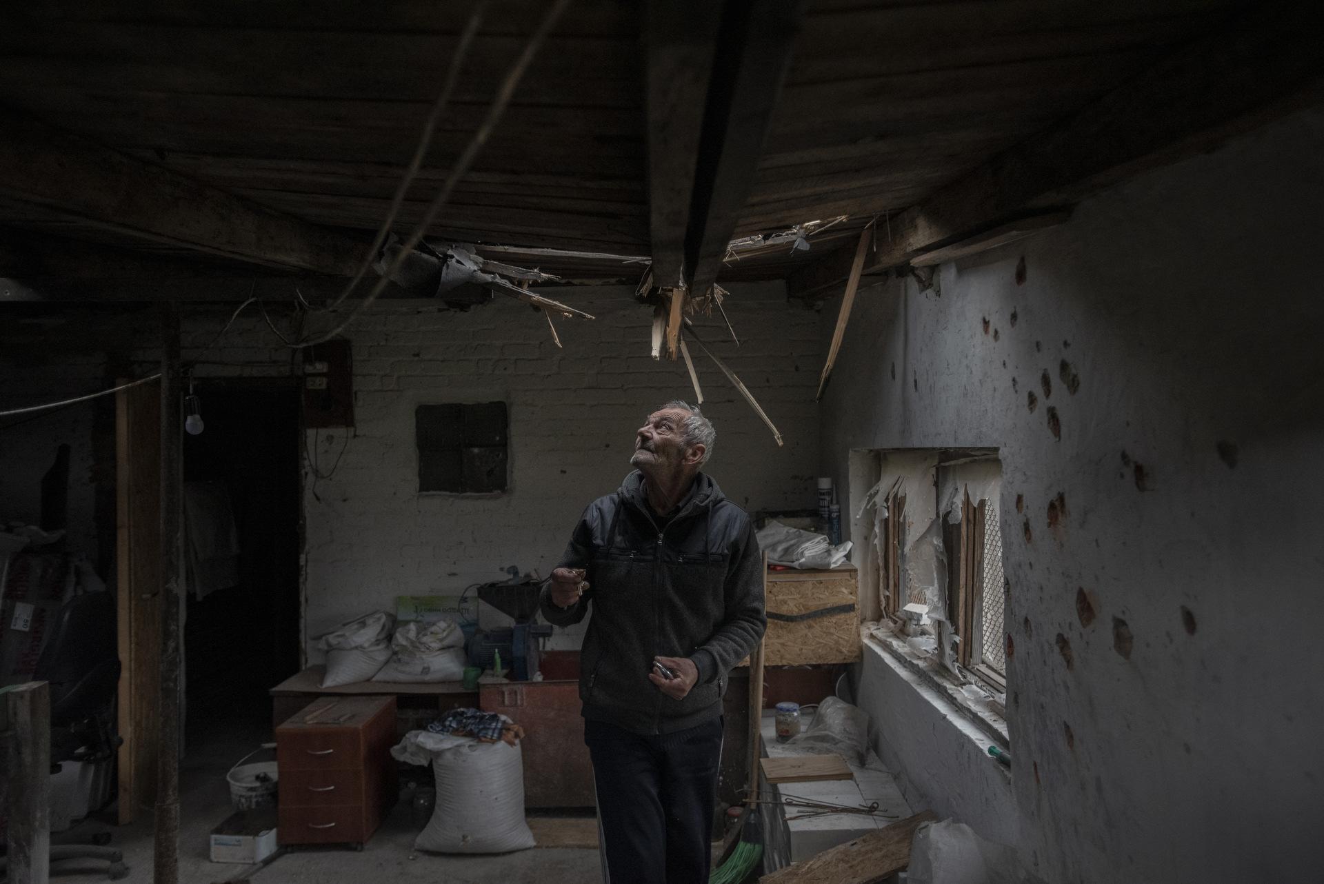 Portfolio Ukraine - A man inside his house watching the hole that a mortar...