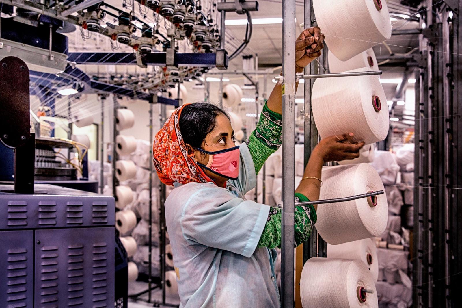 A textile worker is working inside factory. Tongi, Bangladesh
