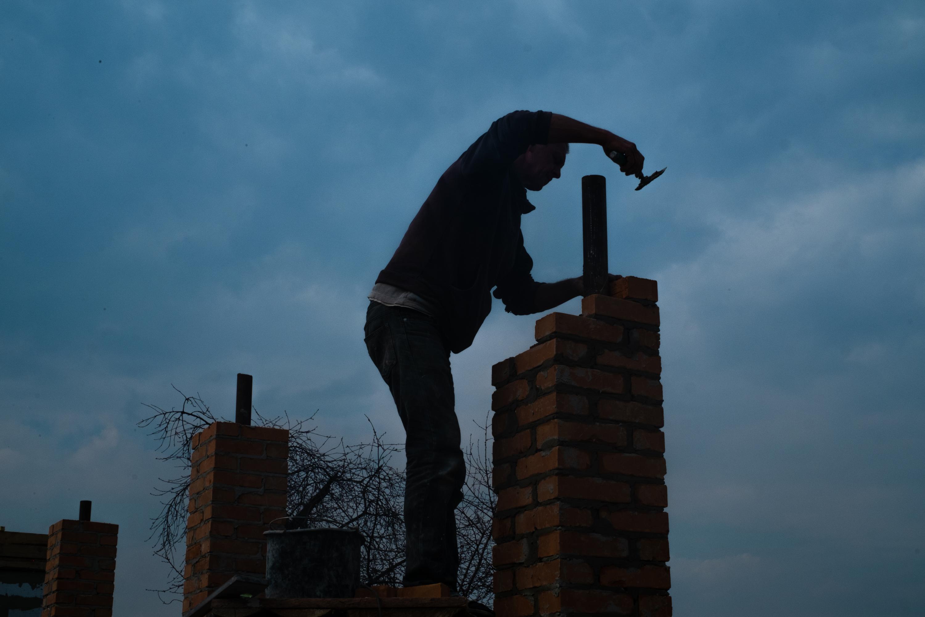 THE RETURN OF VIKA -   A man rebuilding the chimney of his house destroyed by...