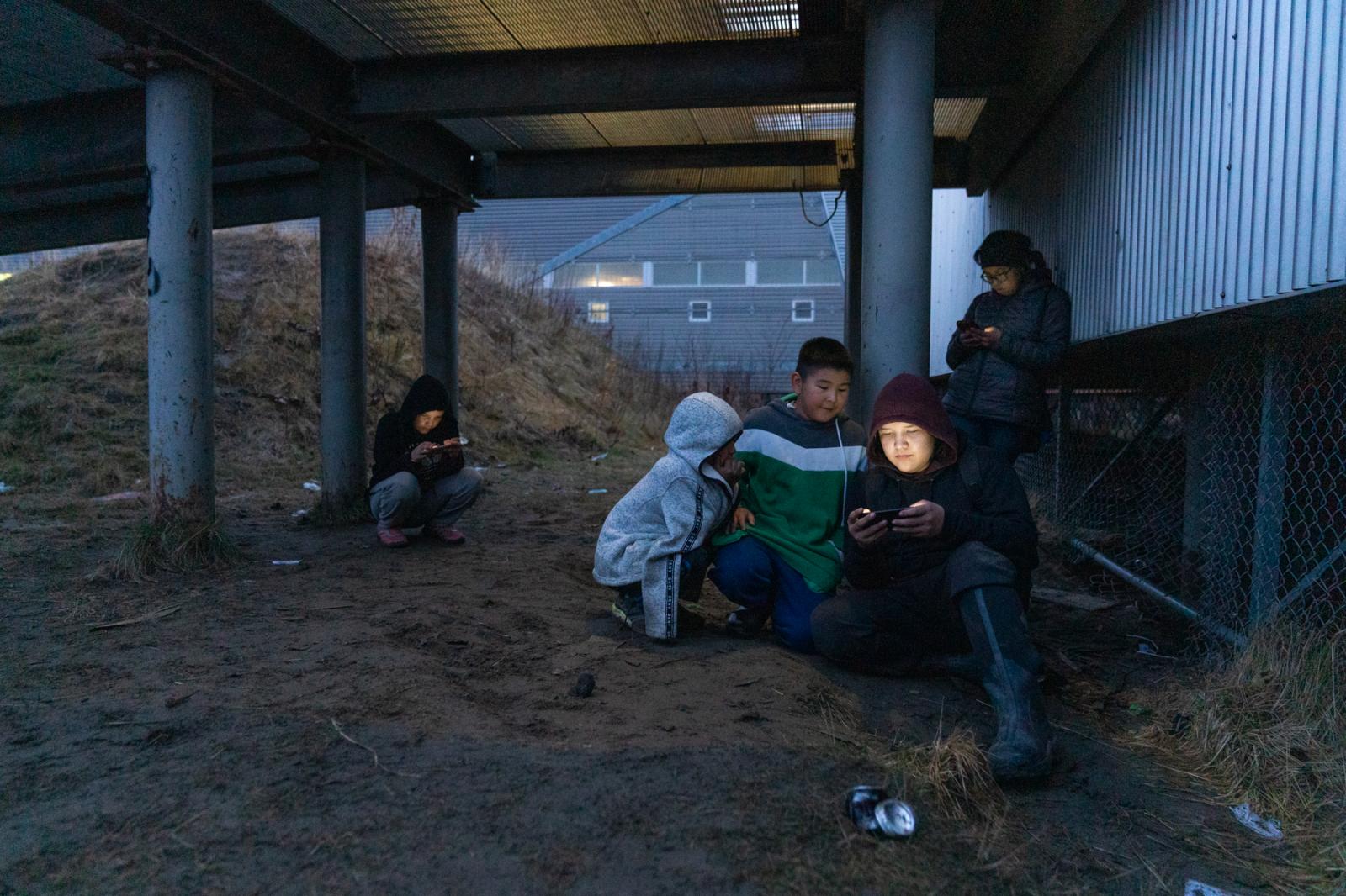 Youth hang out near the school in Akiak, Alaska to access wireless internet through their phones....