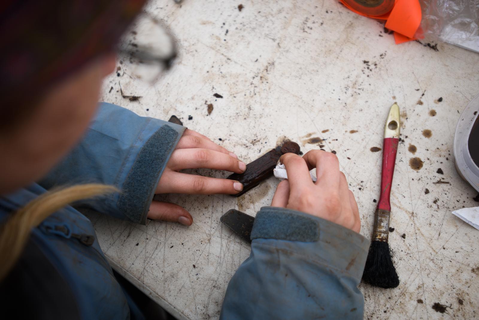 Archeology student Lauren Phillips cleans a wooden doll found at the Nunalleq site near Quinhagak...