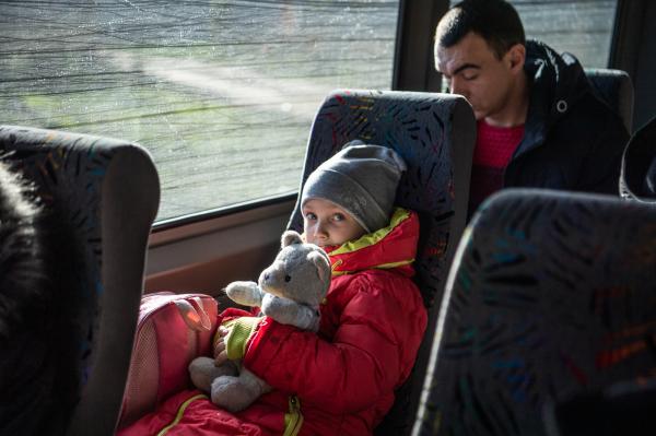 Image from Ukraine - A young girl holds a teddy bear while sitting on an...