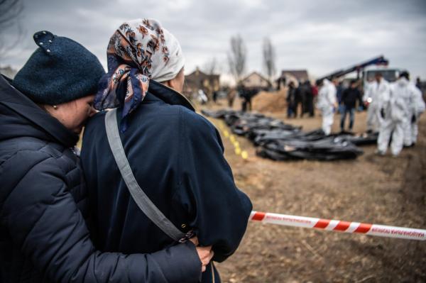 Image from Ukraine - Two women embrace in front of a mass grave in Bucha, a...