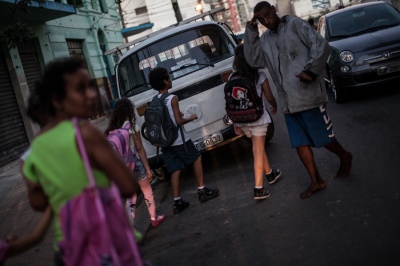  In the historic city center of SÃ£o Paulo, Brazil, commuters and families walk through the CracolÃ¢ndia district. Here, a woman with a baby and schoolchildren pass by a crack addict. 