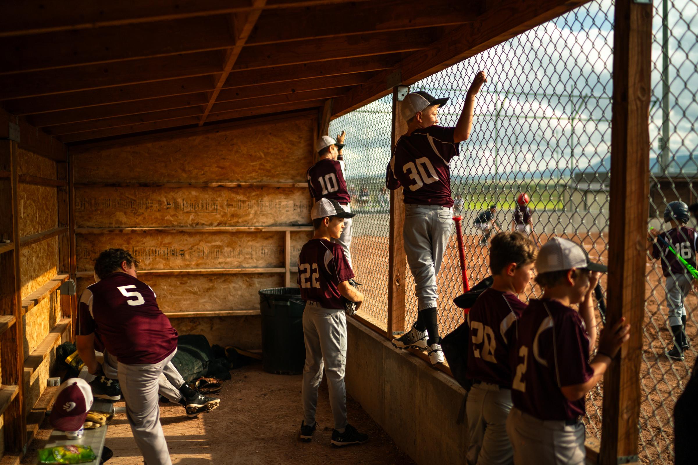 Singles - Little League players watch as a team mate goes to bat on...