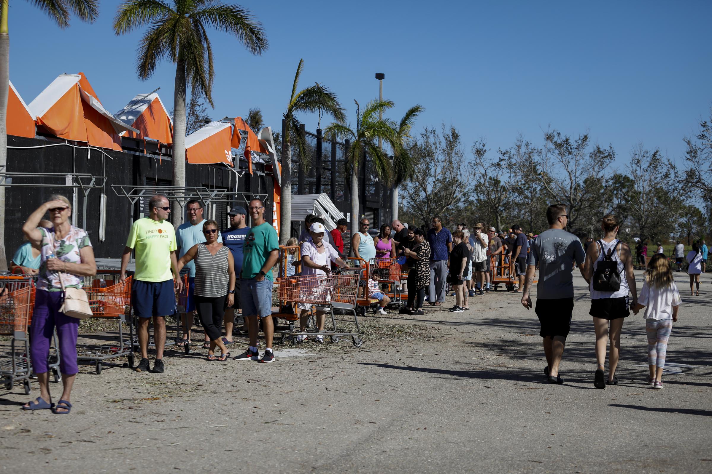 2022 - Hurricane Ian - Customers wait in line to enter a Home Depot store...