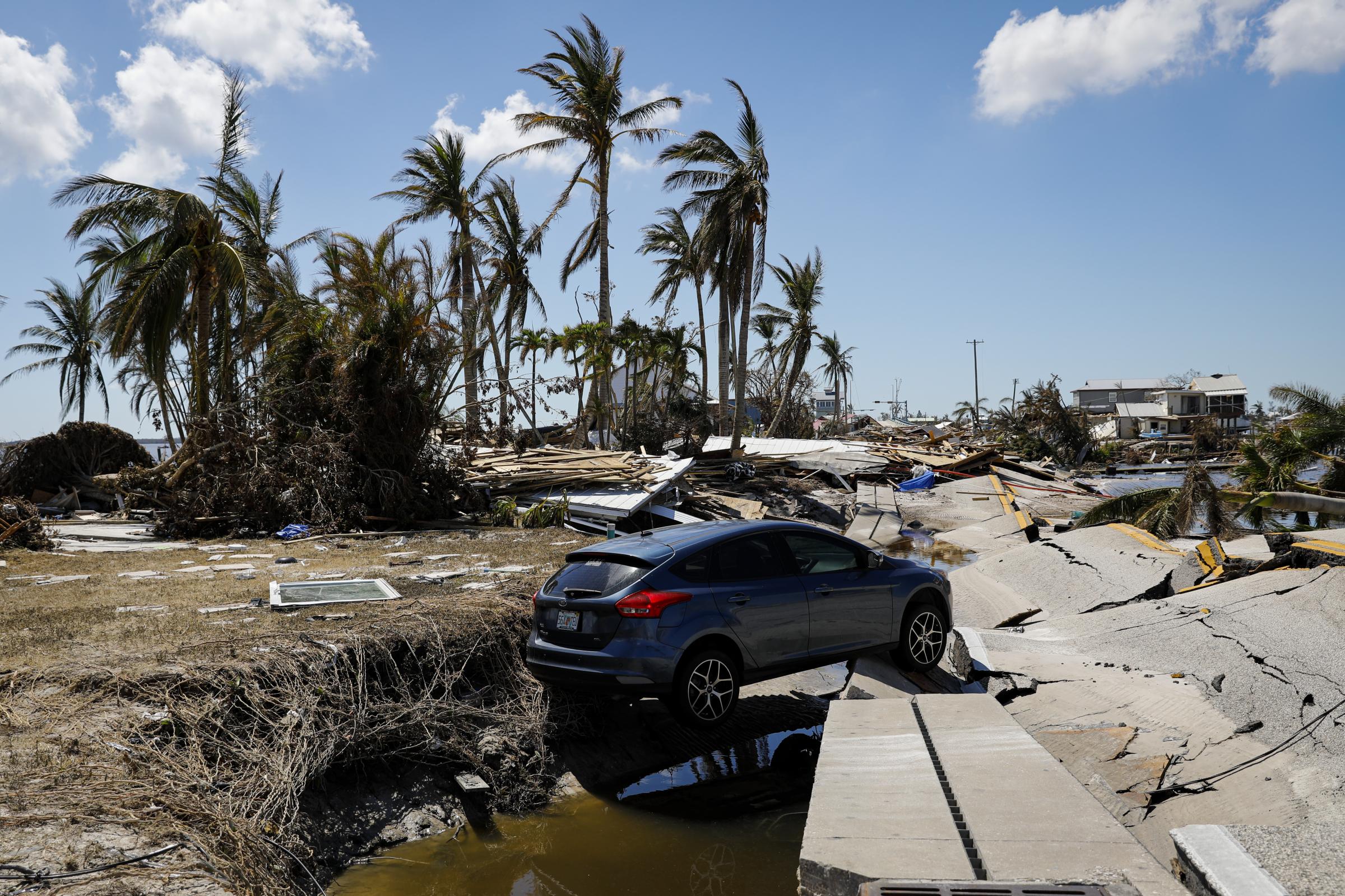 2022 - Hurricane Ian - A car stand over the debris of a main street following...