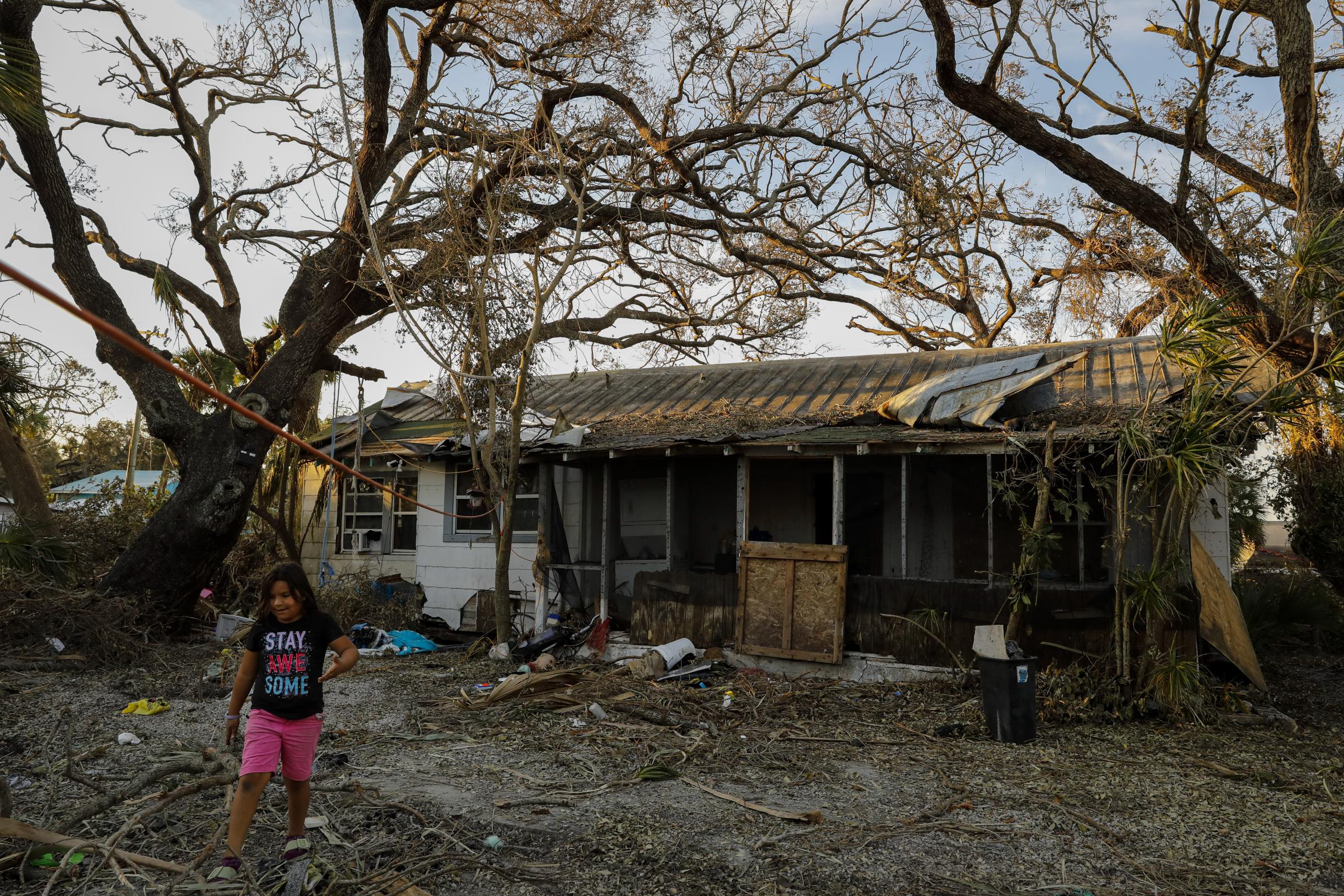 2022 - Hurricane Ian - A child walks next to damaged house at San Carlos Island...