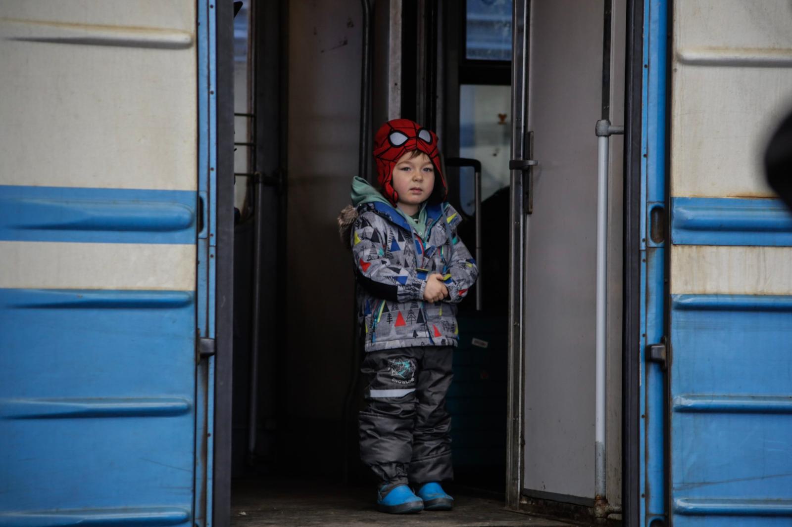 A boy dressed in a Spider-Man hat watches people on the platform of the station in Lviv, Ukraine....