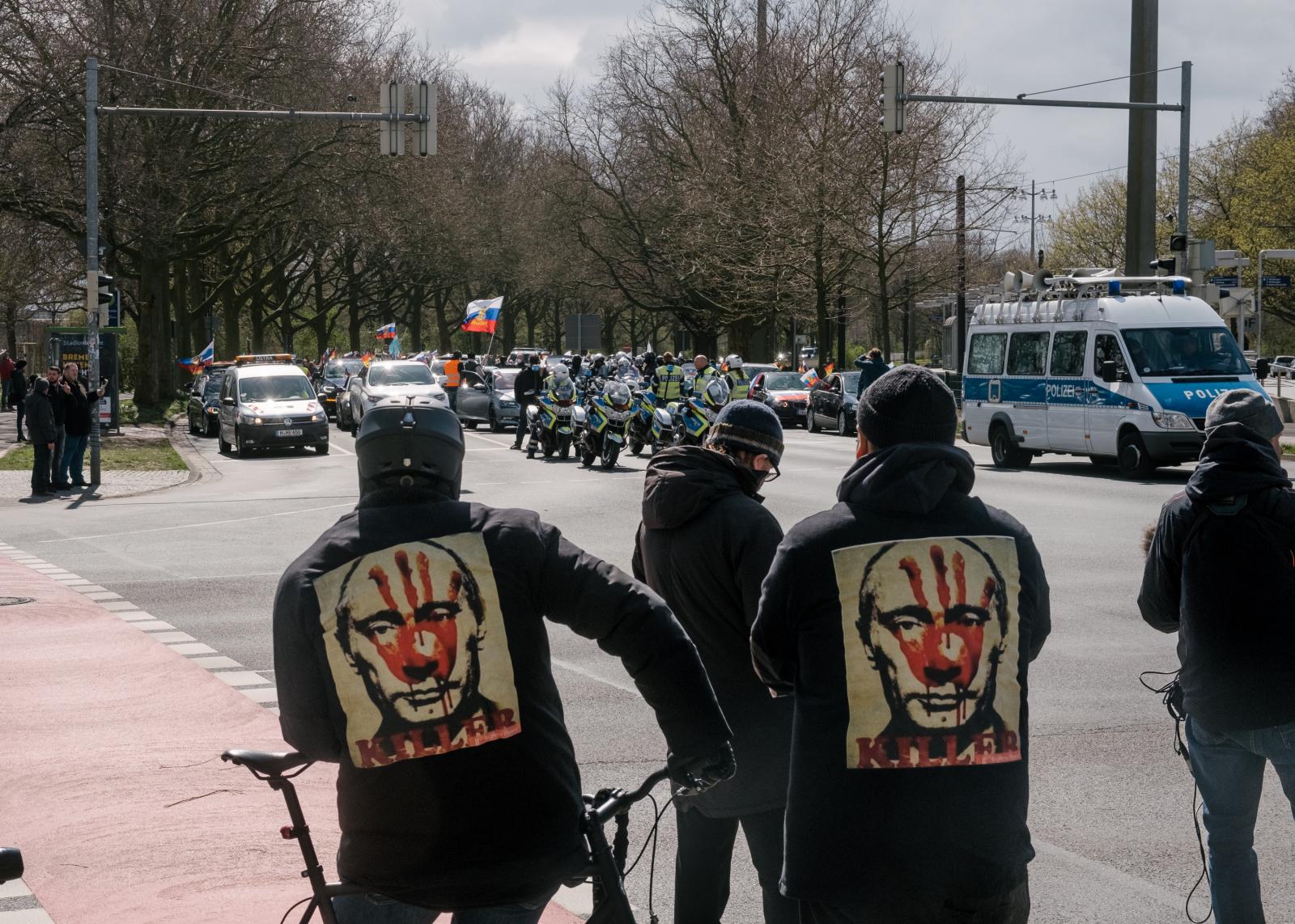 Russian Motorcade in Hanover Blocked - Two men in hoodies with Putin's face and the words...