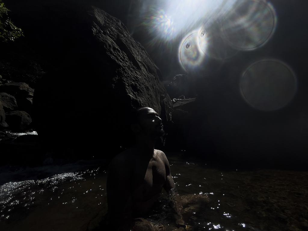 A man is meditating in a secret waterfall in Maharashtra. 