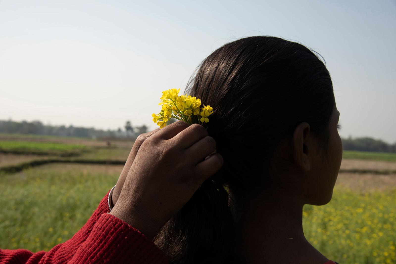 A girl is putting mustard flowe...a district, West Bengal, India.