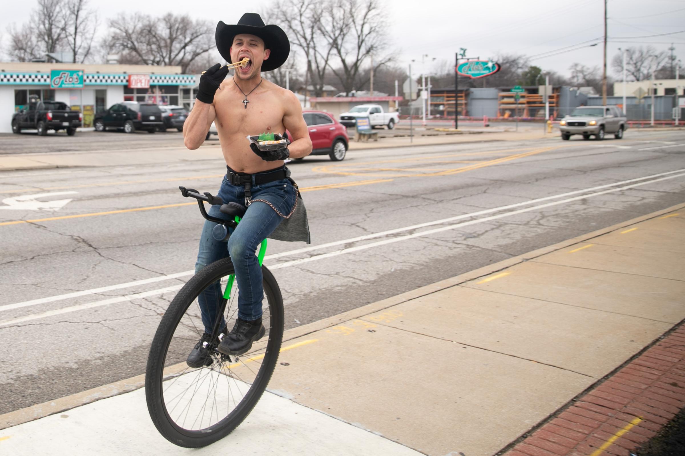 News - Josiah Ferrill rides his unicycle down the sidewalk along...