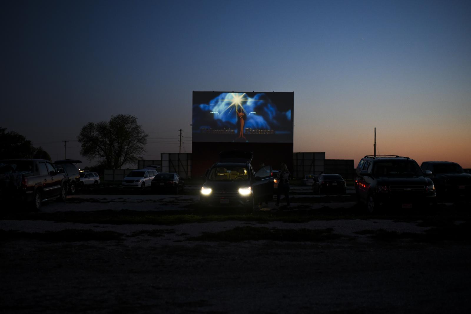 People sit in their cars as the... the ground to watch the movie.