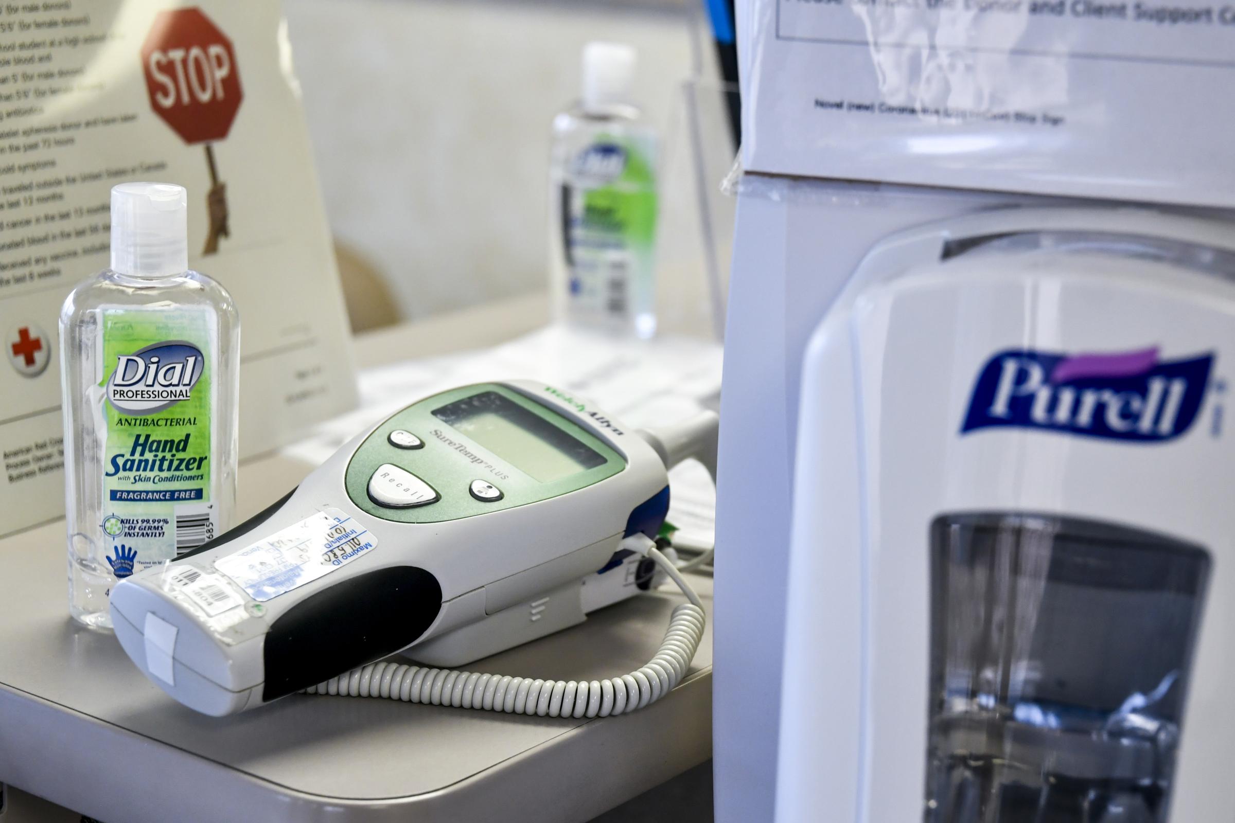 Bottles of hand sanitizer and a thermometer are placed on the front desk on Wednesday, March 18, 2020, at the Red Cross Blood Donation Center in...