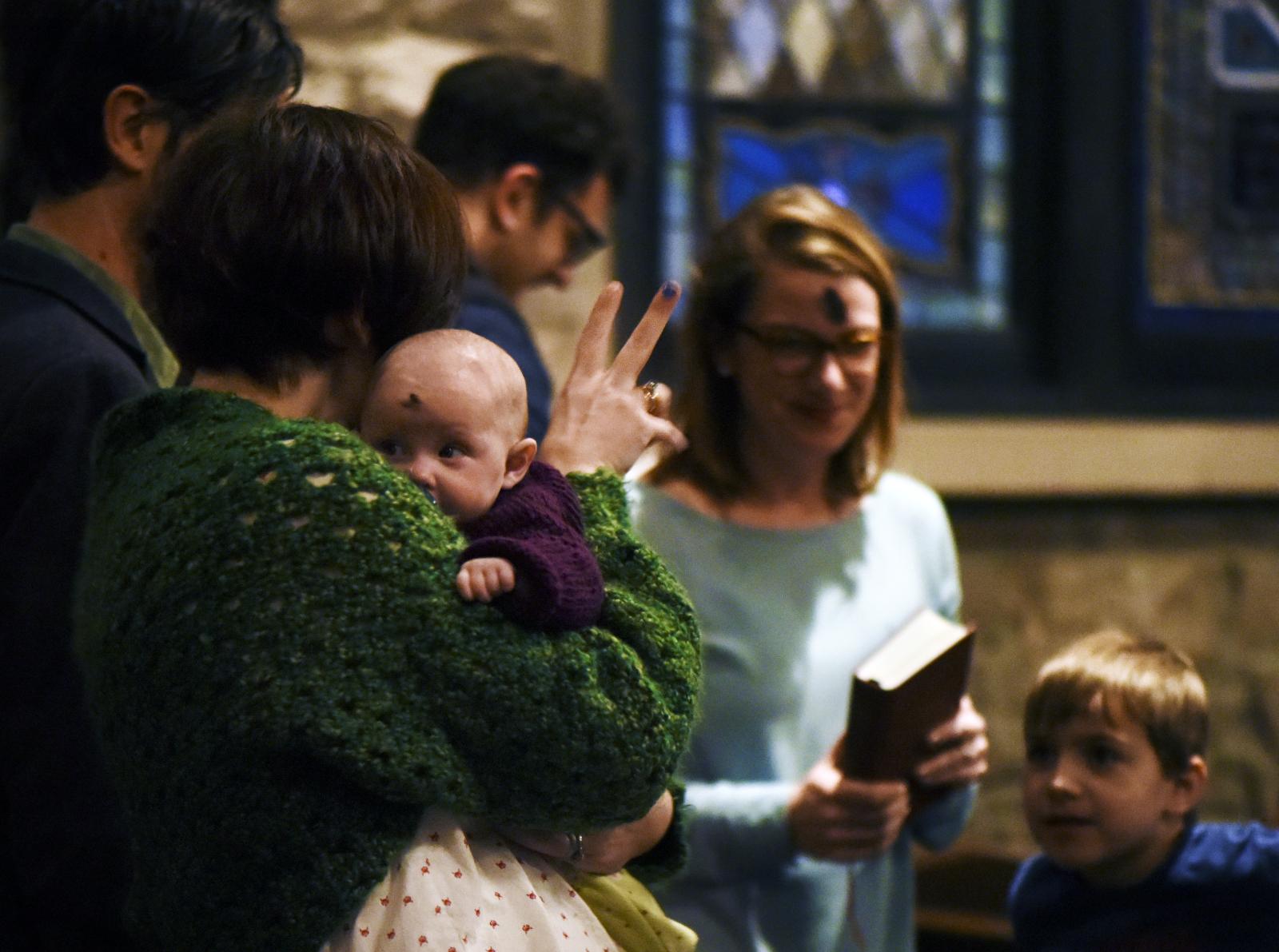 Morgan Owen passes the peace to other members of the congregation while holding her daughter, Hollis Owen, during the Ash Wednesday service on February 26, 2020, at Calvary Episcopal Church in Columbia, Missouri. Ash Wednesday signifies the beginning of Lent for some Christian denominations.